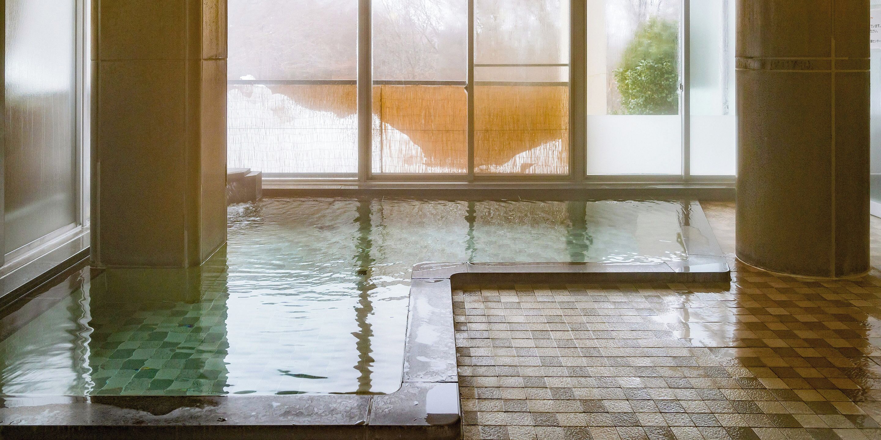 A wet indoor pool with clear water, tiled floor, and large windows.