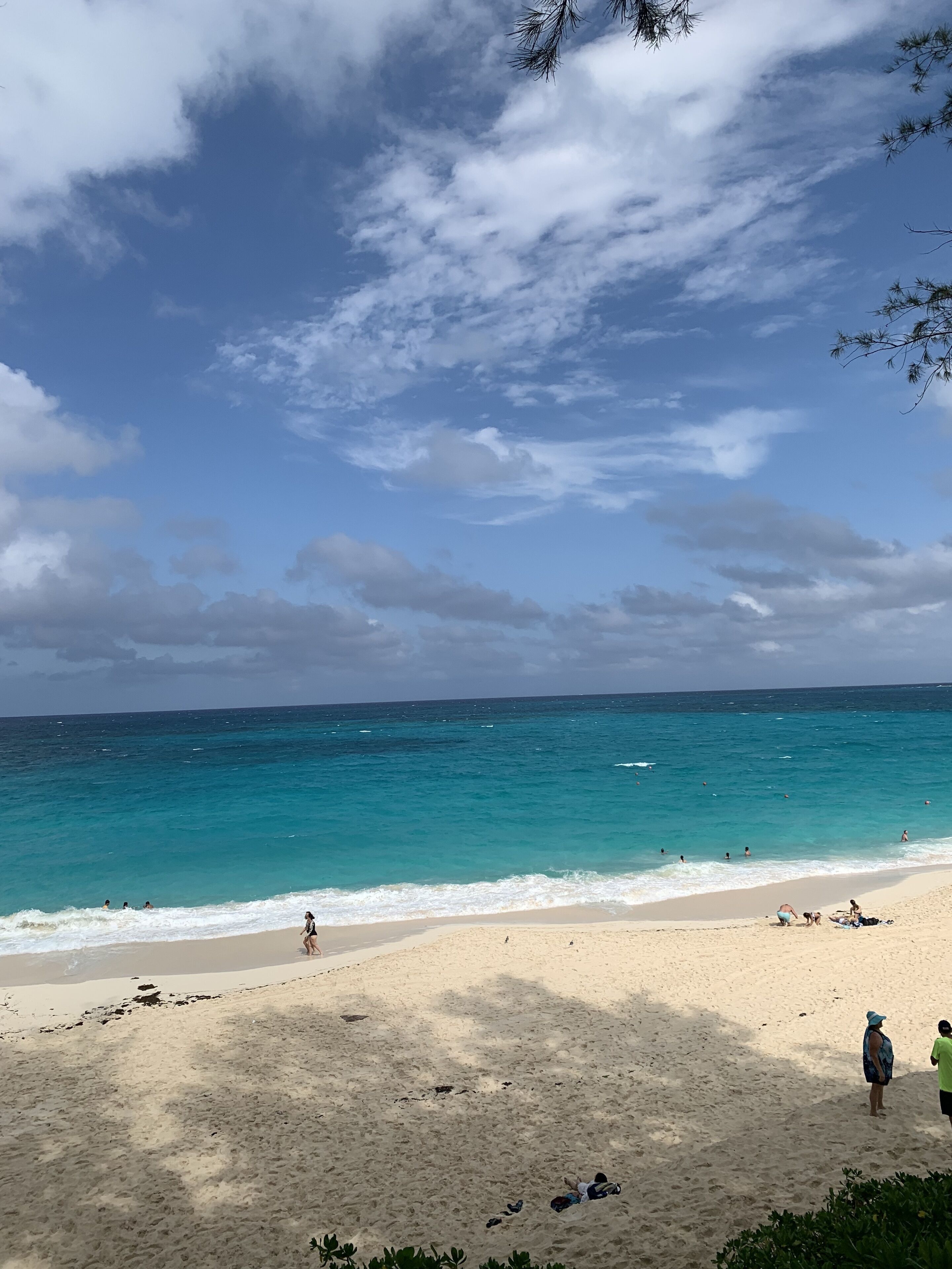 A beach with clear turquoise water, a sandy shore, and a few people enjoying the beach.