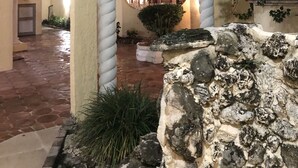 Ein Innenhof mit einem steinernen Bogen, einer Palme und einem Gebäudeeingang mit Balkon.