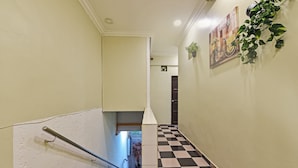 Un couloir avec un sol à carreaux, une main courante et une porte au fond.
