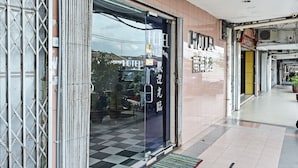 L’entrée d’un hôtel, avec son sol à carreaux, un panneau d’accueil et une porte en verre.
