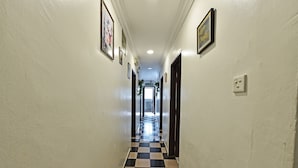 Un couloir avec un sol à carreaux, des murs blancs et des tableaux encadrés.