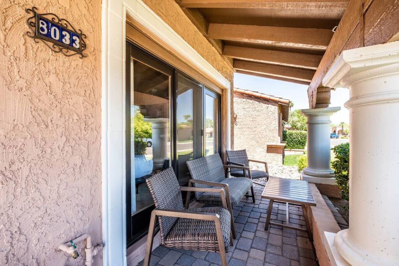 A covered patio with wicker furniture and a stone wall.