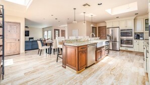 A spacious kitchen with a large island, modern appliances, and a dining area with a sofa and chairs. - McCormick Ranch Oasis (Scottsdale)
