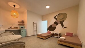 Ein modernes Zimmer mit zwei Betten, einer Essecke und einer Küchenzeile.
