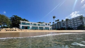 A beachfront hotel with a modern design, featuring multiple floors and large windows. - Corcega Beachfront Suite with Balcony in Rincon (Aguada)