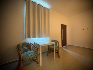 Cozy room with a table and chairs, featuring a woven design, and a window with a curtain.