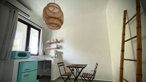 Una cocina compacta con una mesa y sillas, un microondas, un refrigerador pequeño y una lámpara colgante.