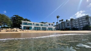 Um imóvel à beira-mar com um edifício moderno, águas cristalinas e palmeiras.