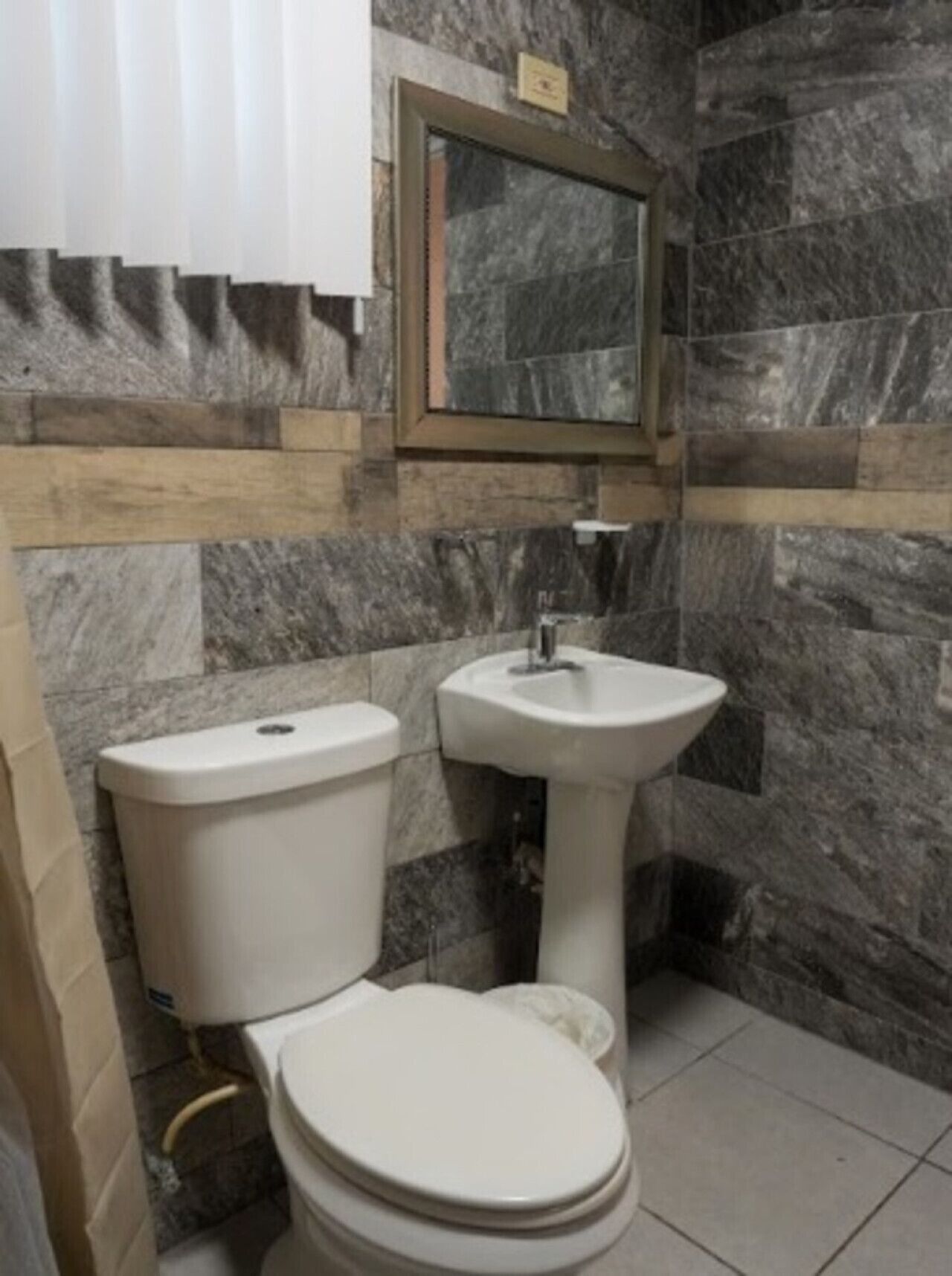 A bathroom with a toilet, sink, and marble walls.