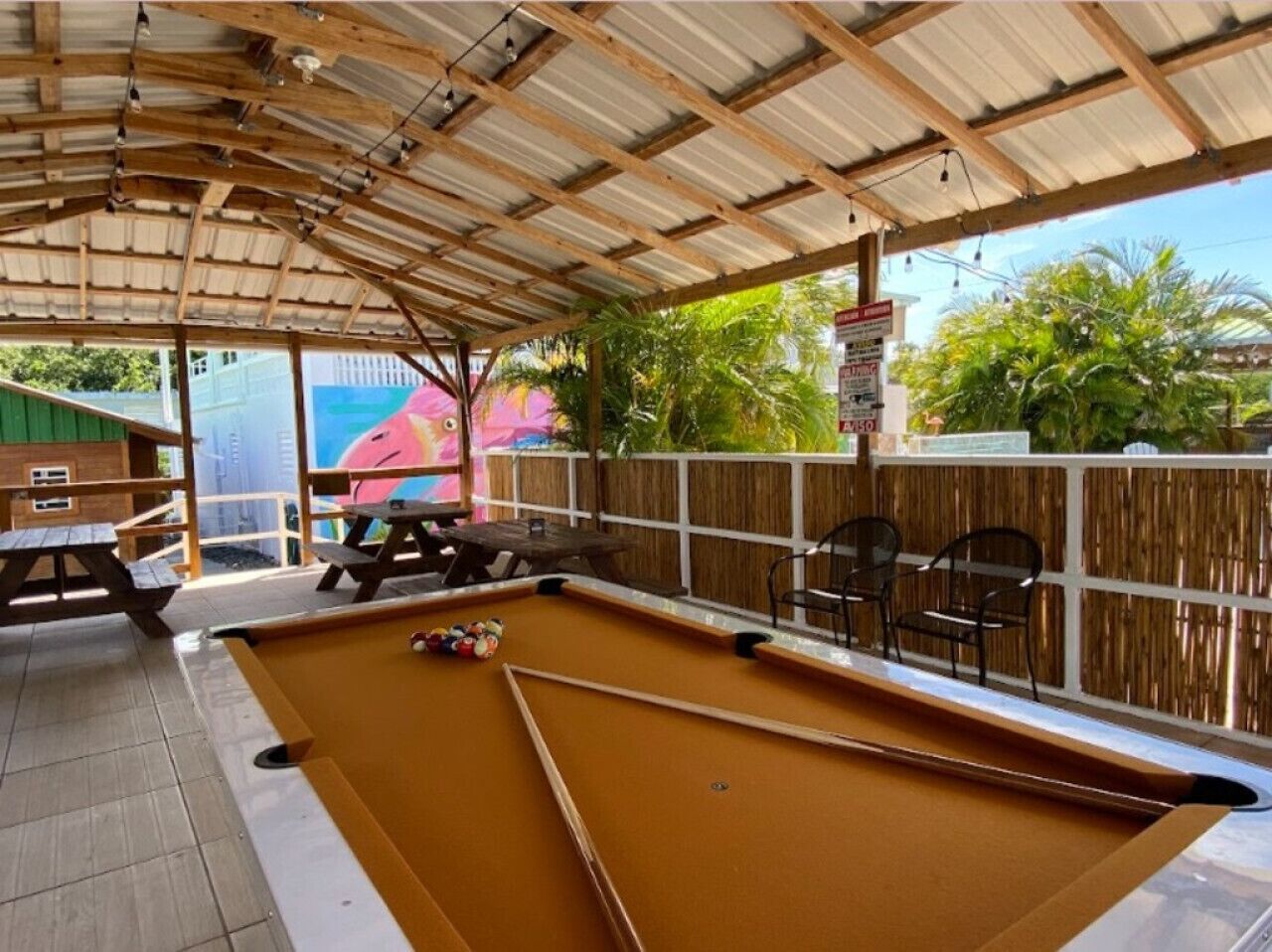 Un espace piscine intérieur comprenant une table de billard, des bancs et un coin salon abrité.