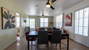 A spacious dining area with a high ceiling fan, large windows, and a view of the outdoors.