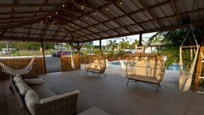 An outdoor patio with wicker furniture, a pool, and a covered area with string lights. - Stylish Studio at El Flamingo Beach Club (Tierras Nuevas Poniente)