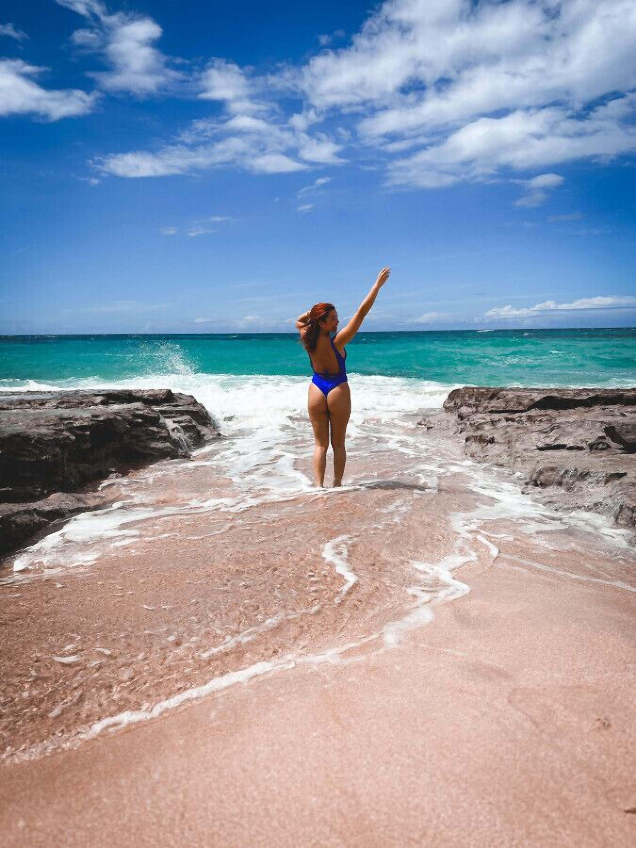 Iemand staat op het strand, met heldere lucht en turquoise water.