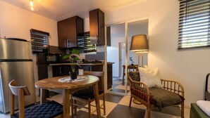 A compact living space with a kitchenette, a dining table with chairs, a sofa, and a lamp. - Stylish Studio at El Flamingo Beach Club (Tierras Nuevas Poniente)
