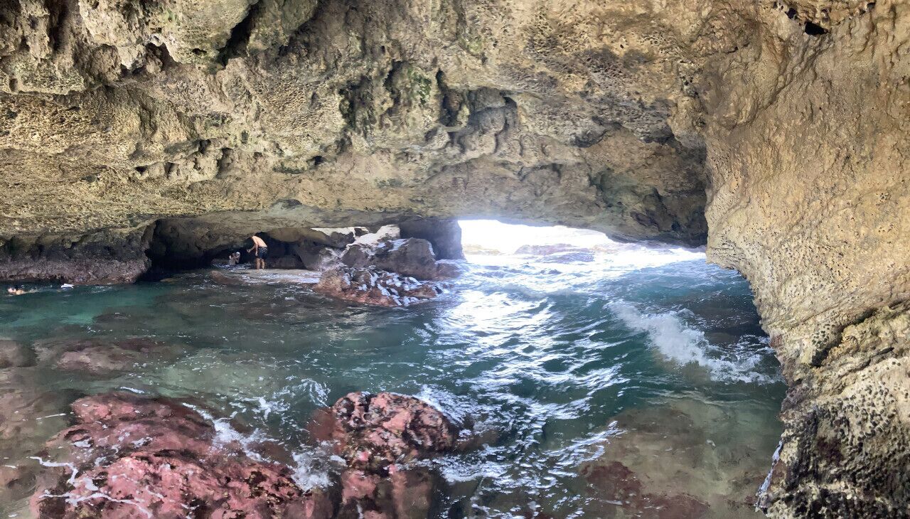 A natural cave with clear water and rocky formations.