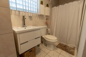 A bathroom with a white sink, toilet, and shower curtain. - 1 BR Apartment at El Flamingo Beach Club (Tierras Nuevas Poniente)