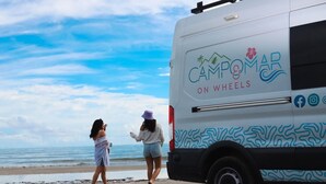 Un camper con la scritta "Camp & Mar" parcheggiato su una spiaggia.