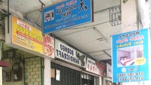 Une rangée de boutiques fermées, avec différentes enseignes annonçant des services tels que des travaux de bricolage et la location de chambres.