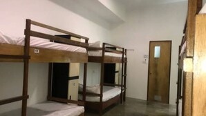 Une chambre de dortoir avec des lits superposés, une porte en bois et une petite fenêtre.