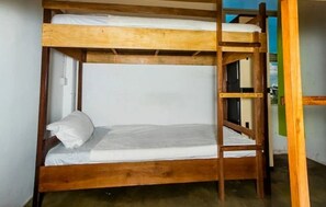 Een stapelbed met houten frame, witte beddengoed en een ladder.