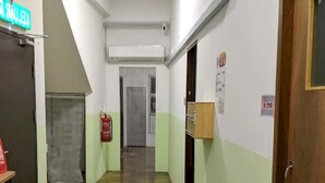 Un couloir avec un extincteur, une porte dotée d’une poignée et un panneau fixé au mur.