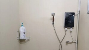 Un petit espace douche fermé, équipé d’un pommeau de douche à main et d’un panneau de commande fixé au mur.