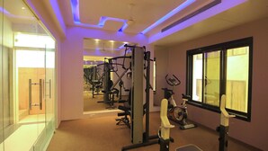 Uma academia com equipamentos de ginástica, um espelho e uma janela com cortinas.