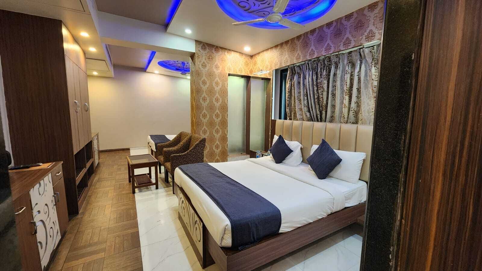 Une chambre d’hôtel avec un grand lit, un bureau, deux chaises et une armoire.