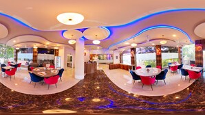 Um restaurante moderno com áreas de estar curvas, piso de mármore e iluminação ambiente.