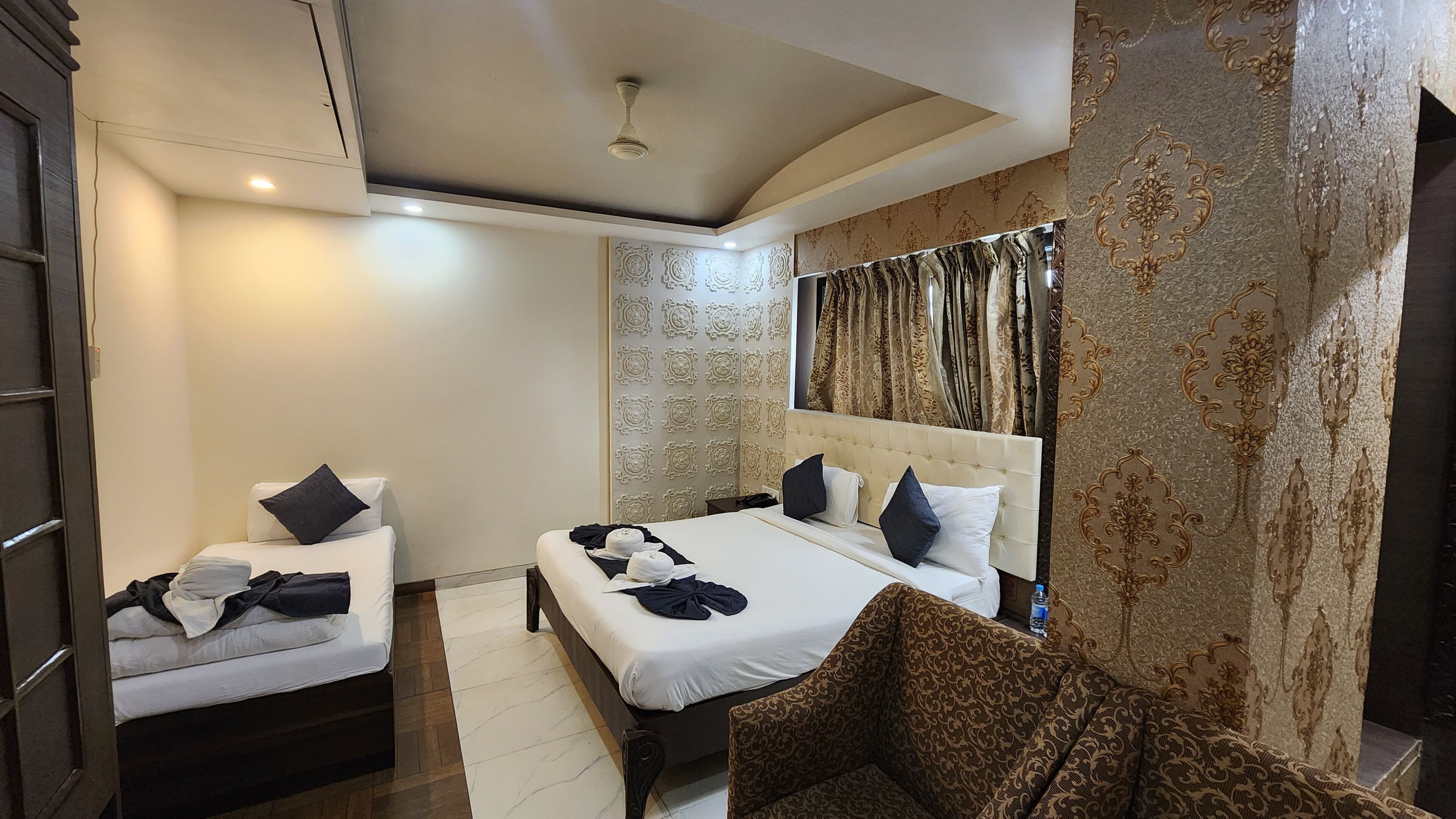 Une chambre d’hôtel avec un grand lit, deux tables de chevet, une chaise et une tête de lit décorative.