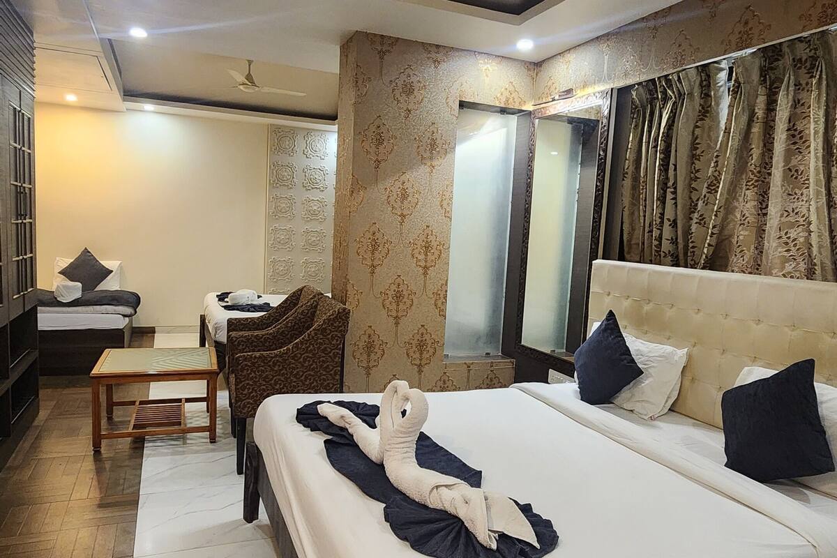 A hotel room with a large bed, a desk, a chair, and a ceiling fan.