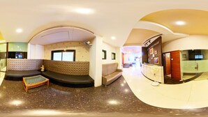 Um lobby moderno com área de estar em curva, balcão de recepção e divisória de vidro com um aviso.