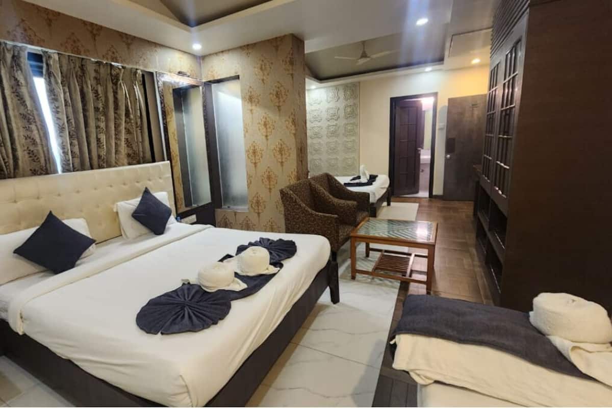 A hotel room with a large bed, a sitting area with a chair, a small table, and a wardrobe.