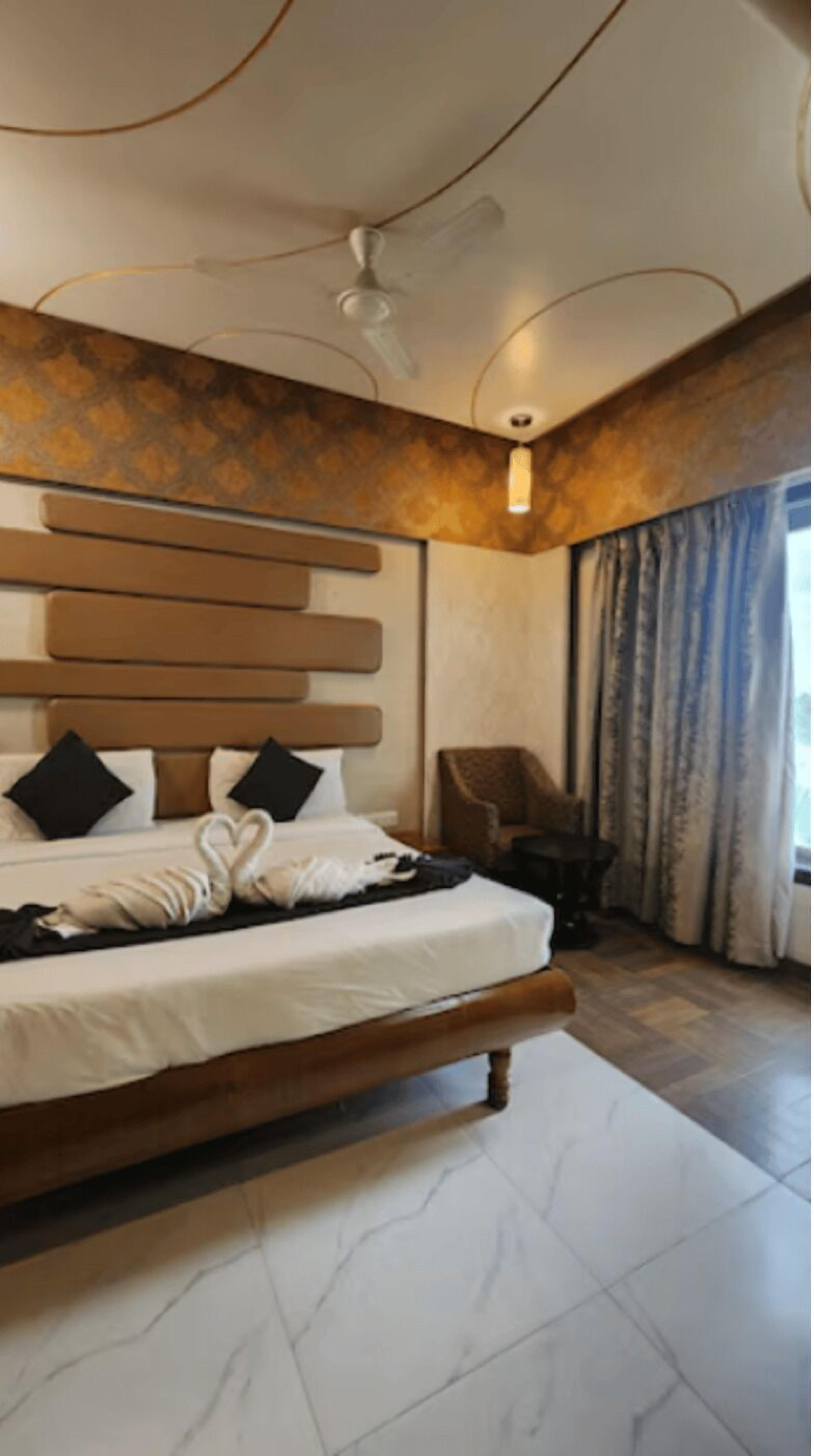 Un dormitorio moderno con una cama grande, un ventilador de techo y vistas al exterior a través de cortinas.