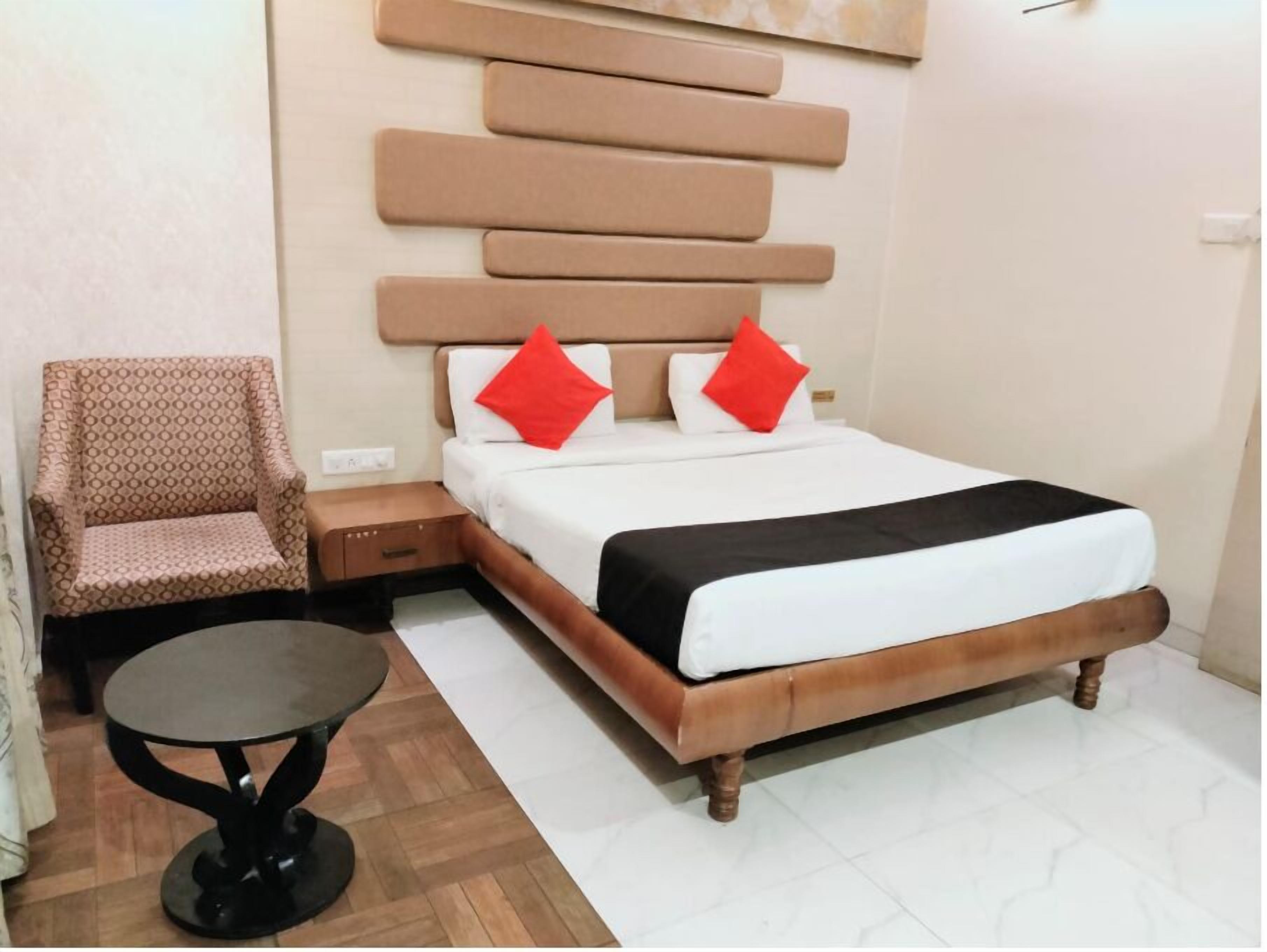 Una habitación de hotel con una cama, una silla, una mesita y una pared con un diseño geométrico.