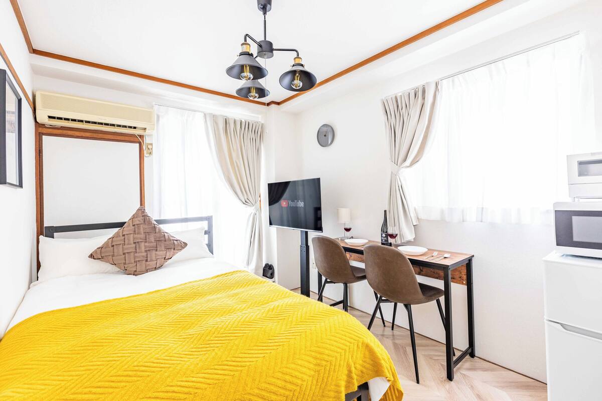 Une chambre d’hôtel équipée d’un lit, d’un bureau, d’une télévision et d’un mini-bar.