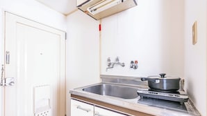 A kitchen with a stainless steel sink, a stove, and a white door. - Esterrace Osaka West (Osaka)