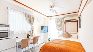 A hotel room with a bed, a desk with a computer, a chair, a TV, and a microwave. - Esterrace Osaka West (Osaka)