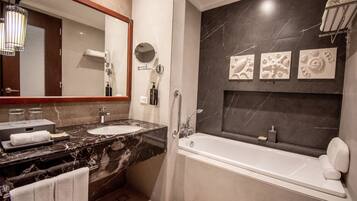 A modern bathroom with a marble vanity, a large mirror, a bathtub, and decorative wall art.