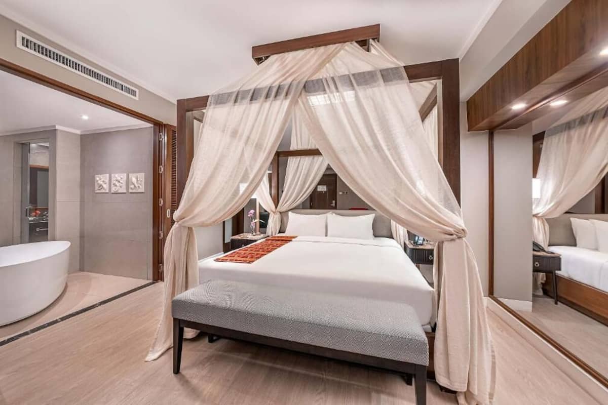 Un dormitorio moderno con cama con dosel, una mesita de noche, un espejo y un baño con bañera.
