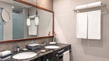 A modern bathroom with two sinks, a large mirror, and a towel rack.