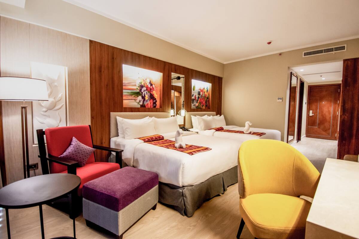 Una habitación de hotel con cama, dos sillas, una mesa y obras de arte en las paredes.