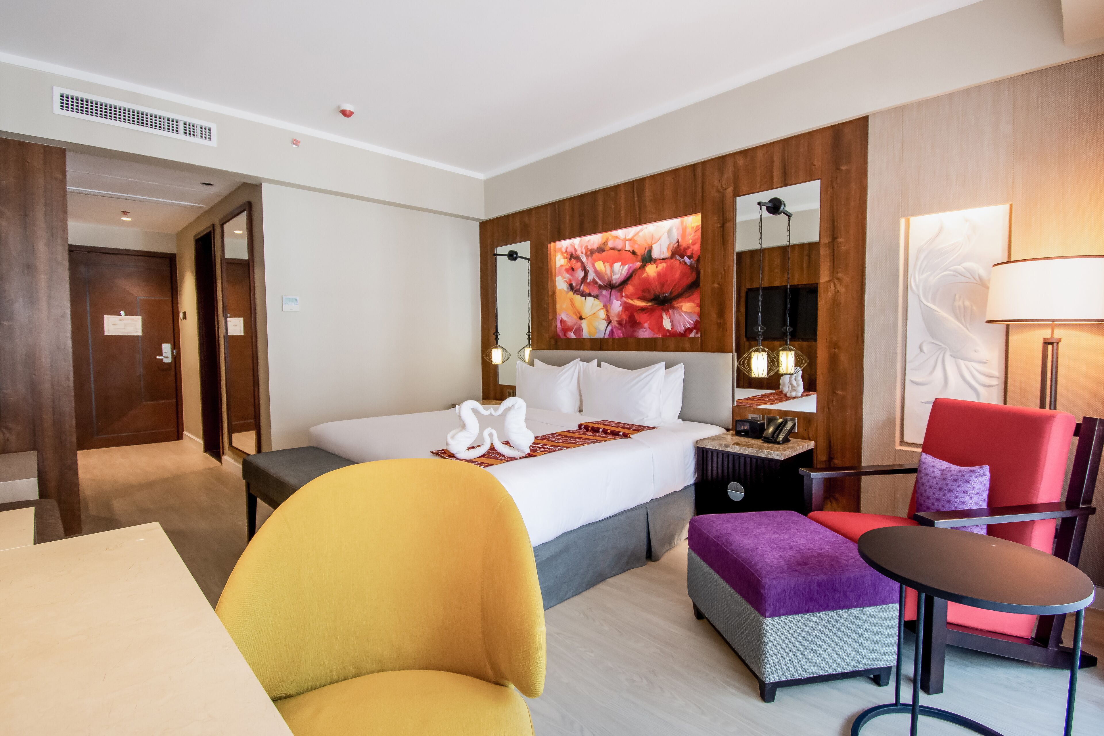 Una habitación de hotel con cama, escritorio, silla, mesa y lámpara.