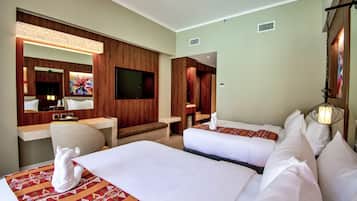 A hotel room with two beds, a sitting area, a TV, and a large mirror.