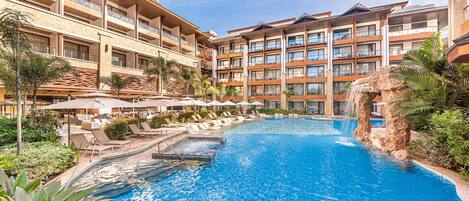 A hotel with a large pool, multiple balconies, and outdoor seating areas.
