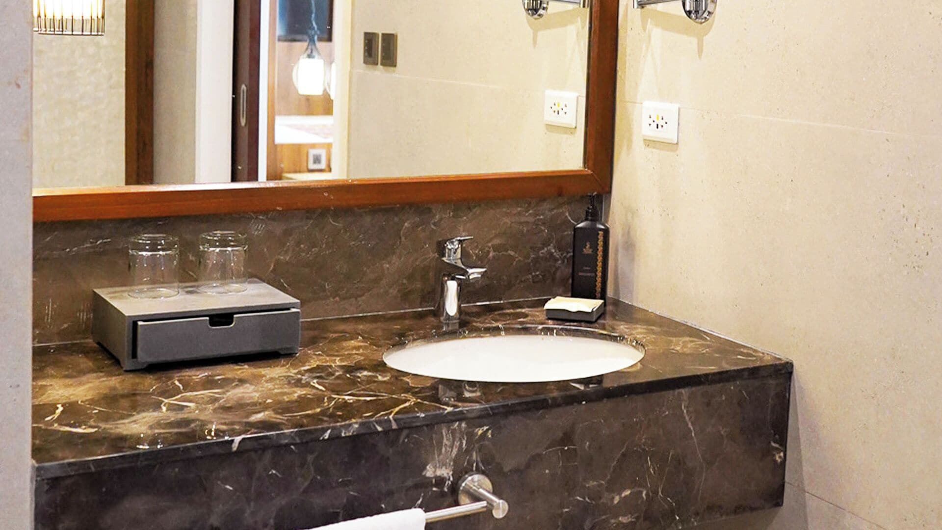 A bathroom with a marble countertop, a sink, a mirror, and a towel rack.
