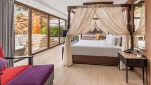 Un dormitorio moderno con una cama grande, un balcón con vistas a rocas y vegetación, y una silla roja.
