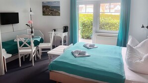 A hotel room with a bed, a desk, a chair, a TV, and a window with curtains. - Hotel und Restaurant Windland (Breege)
