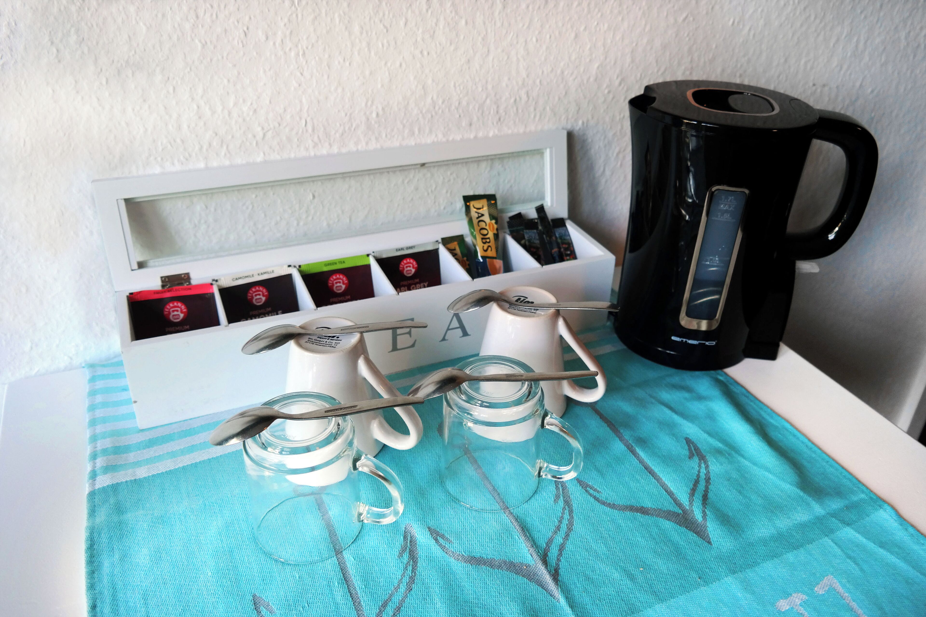 Una cocina con cafetera, bolsitas de té y un escurreplatos.